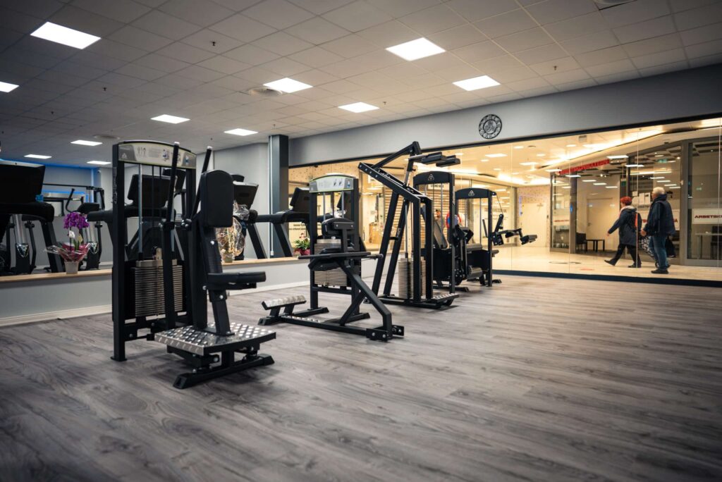 Row of BUGE selectorized gym equipment in modern fitness center.